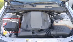 Detailní pohled na pojistkovou skříňku v motorovém prostoru vozidla.